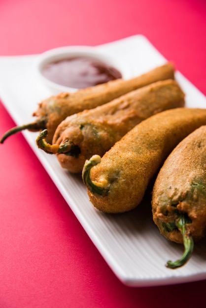 Crispy Green Chilli Pakora ou Mirchi Bajji, servido com ketchup de tomate sobre um fundo temperamental. É um lanche da hora do chá popular da Índia, especialmente na Monção. Foco seletivo