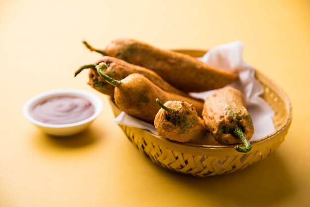 Crispy Green Chilli Pakora ou Mirchi Bajji, servido com ketchup de tomate sobre um fundo temperamental. É um lanche da hora do chá popular da Índia, especialmente na Monção. Foco seletivo