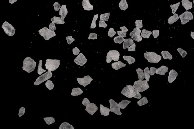Foto cristais grandes e pequenos de sal-gema em um fundo preto.