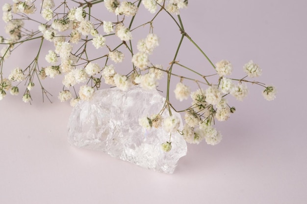 Cristal claro e flores brancas em um fundo roxo claro. conceitue o feng shui
