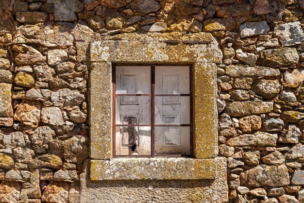 Cristal roto y persianas de madera en la ventana de piedra y la pared de la antigua casa en la antigua ciudad de Castelo Rodrigo en Portugal