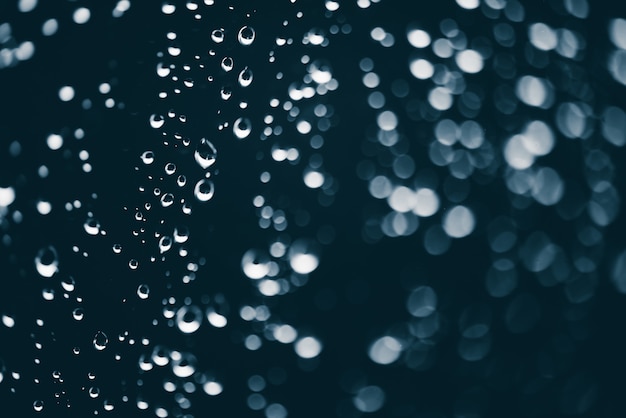 Cristal de la ventana sucia con gotas de lluvia. Fondo azul atmosférico con gotas de lluvia en bokeh. Gotas y manchas de cerca. Textura transparente detallada en macro con espacio de copia. Clima lluvioso.