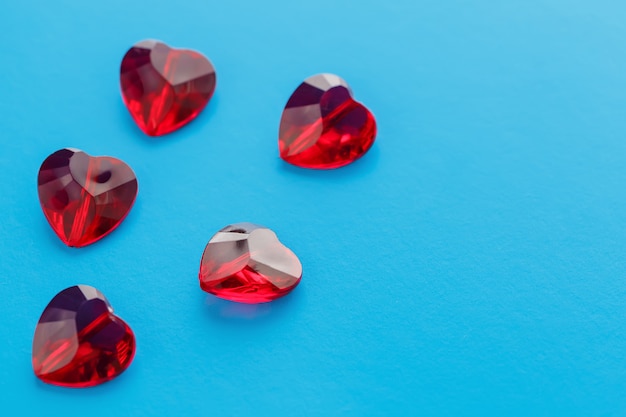 Cristales rojos sobre una superficie azul en forma de corazón, jalea crujientes corazones en la parte superior, vista desde arriba