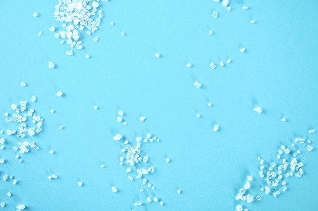 Foto cristales de sal de mar grande sobre una mesa azul.
