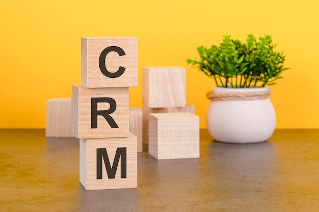 CRM-Text auf Holzwürfeln stapeln gelben Hintergrund