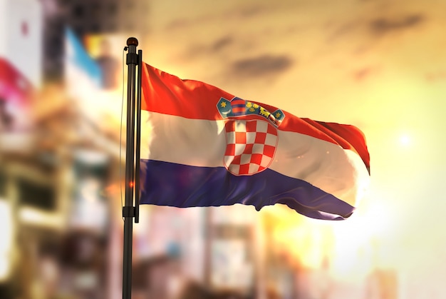 Croacia bandera contra la ciudad borrosa de fondo a la salida del sol retroiluminación