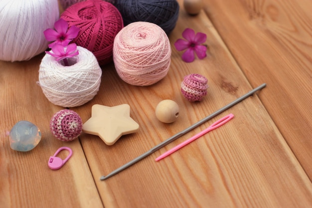 Crochet ganchos e hilo de color rosa y gris, espacio de copia de fondo de madera.