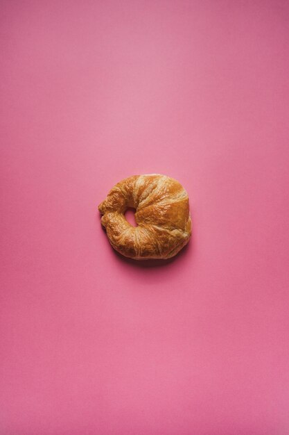 Croissant aislado sobre fondo rosa