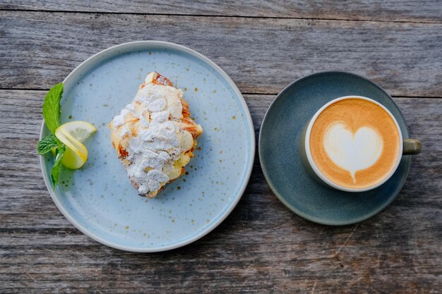 Croissant de almendras y latte de corazón en un entorno artístico al aire libre