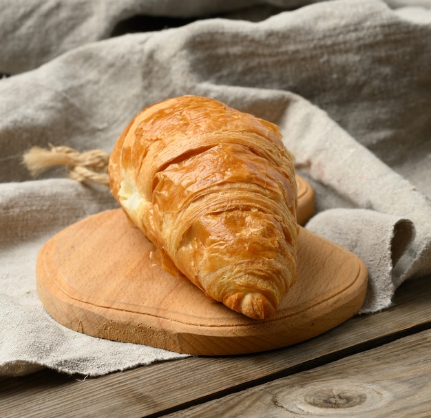 Croissant assado na mesa de madeira, mesa cinza de madeira, close-up