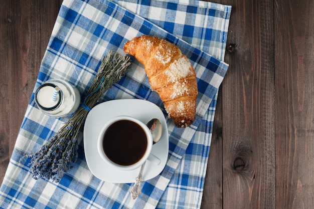 Croissant auf der blauen Serviette auf dem alten Holztisch