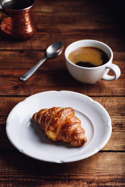 Croissant auf weißem Teller und Tasse türkischen Kaffee