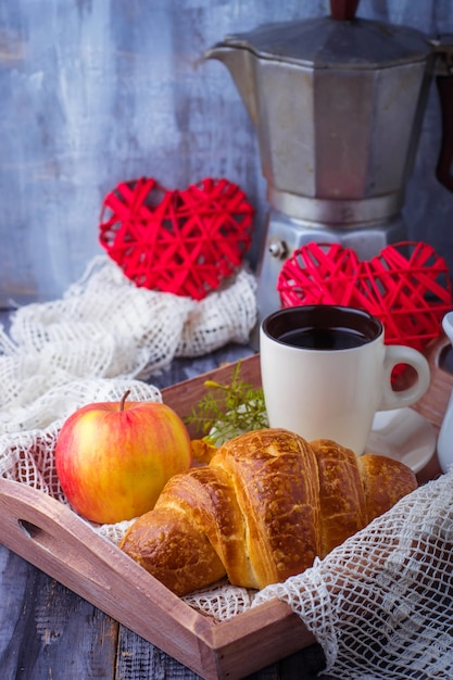 Croissant, café y corazón sobre fondo de madera.