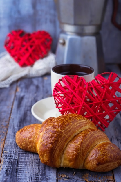 Croissant, café y corazón sobre fondo de madera.