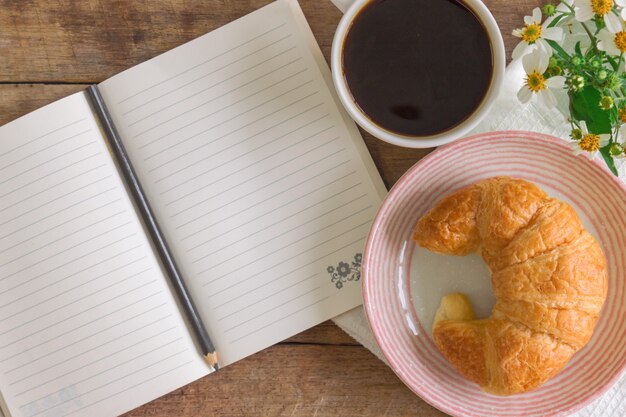 Croissant caseiro no prato servido com café preto ou americano no café da manhã