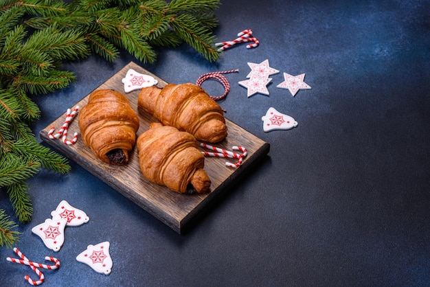 Croissant de chocolate crujiente con adornos navideños en tabla de cortar de madera