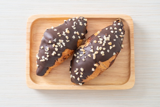 Croissant con chocolate y nuez sobre placa de madera