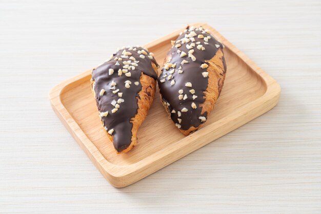 Croissant con chocolate y nuez sobre placa de madera