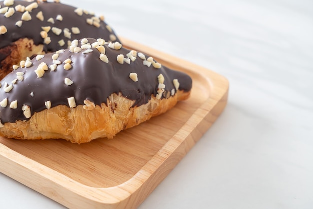 Croissant con chocolate y nuez sobre placa de madera