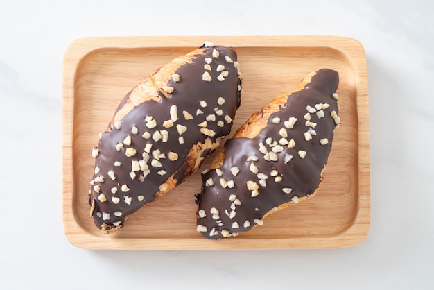 croissant com chocolate e nozes no prato de madeira