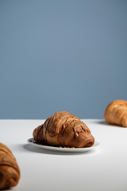 Croissant com chocolate Sobre uma mesa branca e fundo azul um copo de cappuccino