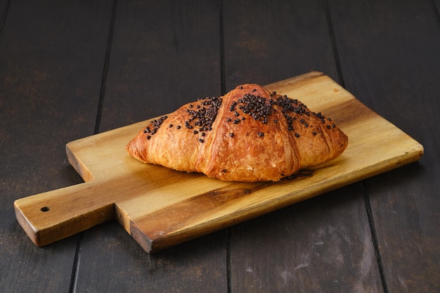 Croissant com cobertura chockolate em uma tábua de servir de madeira