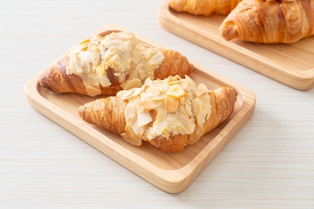 croissant com creme e amêndoas no prato de madeira