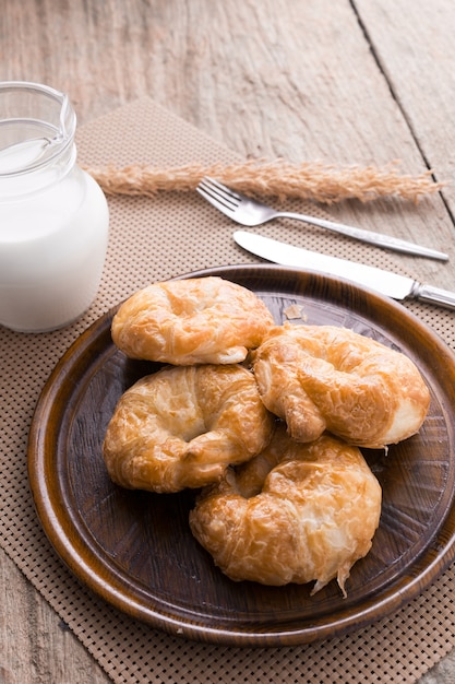 Croissant com leite na mesa de madeira