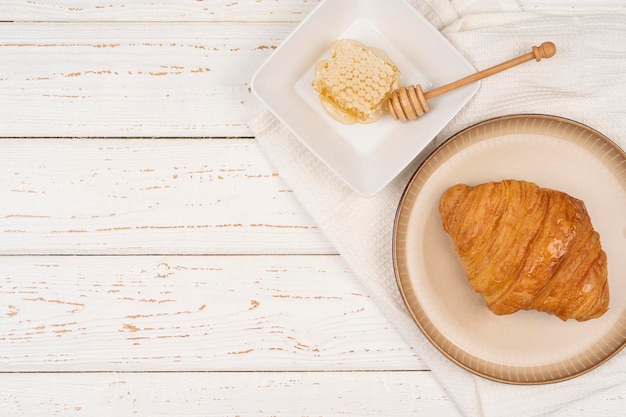 Croissant com sobremesa doce de mel em uma mesa de madeira branca. Fundo brilhante do café da manhã