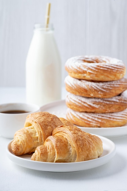 Croissant Cookies Kaffee und Milch auf einem weißen Tisch zum Frühstück