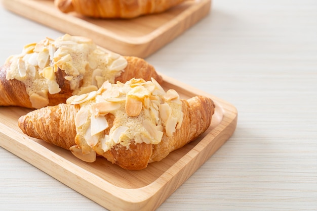 Croissant con crema y almendras sobre placa de madera