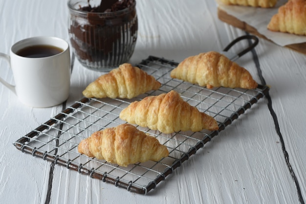 croissant Croissants frescos assados em uma bandeja com um pequeno pote de geleia para o café da manhã