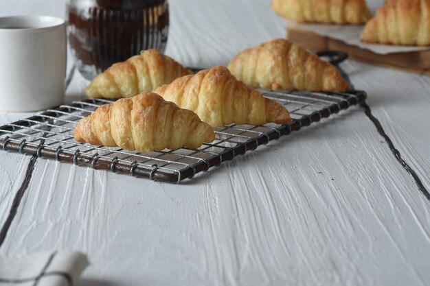 croissant Croissants frescos assados em uma bandeja com um pequeno pote de geleia para o café da manhã