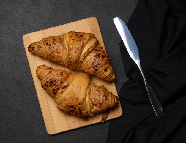 Croissant crujiente al horno sobre una tabla de madera desayunox9