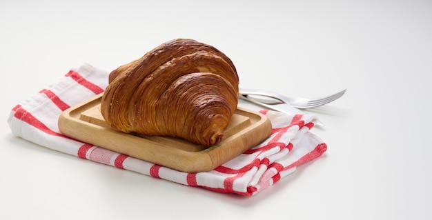 Croissant crujiente horneado en tabla de madera mesa blanca desayuno