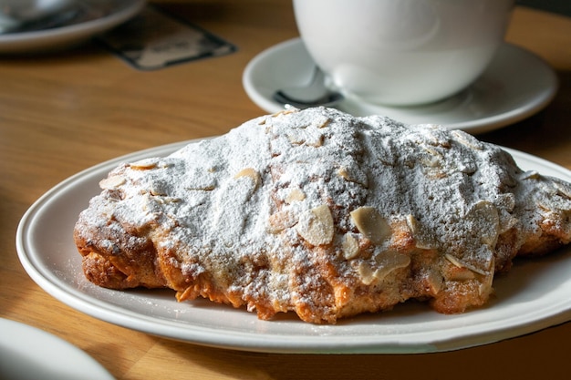 Croissant de amêndoa em um prato com foco seletivo de sombra fechado