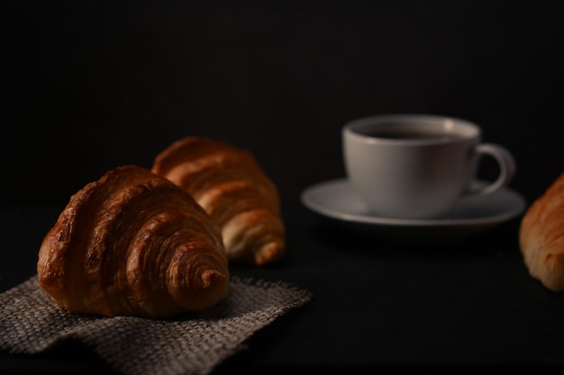 Croissant de manteiga caseira e xícara de café na mesa de madeira Conceito de café de produtos de padaria de pão de levitação