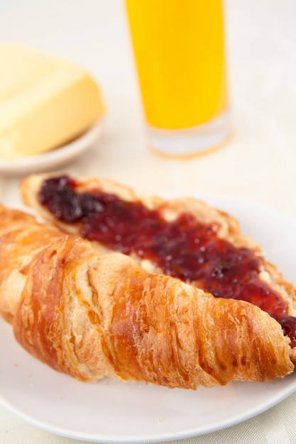 Croissant delante de un vaso de jugo de naranja