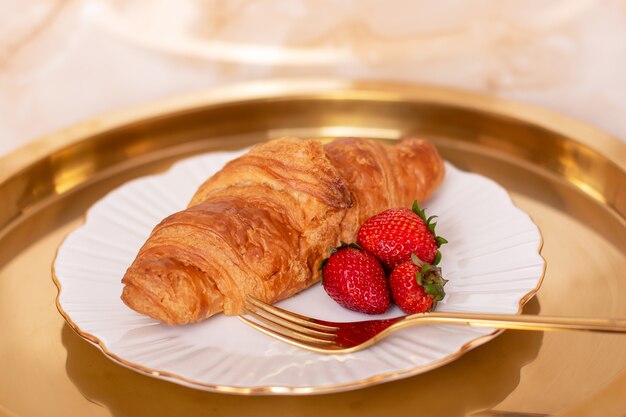 Croissant doce com morango fresco em prato dourado