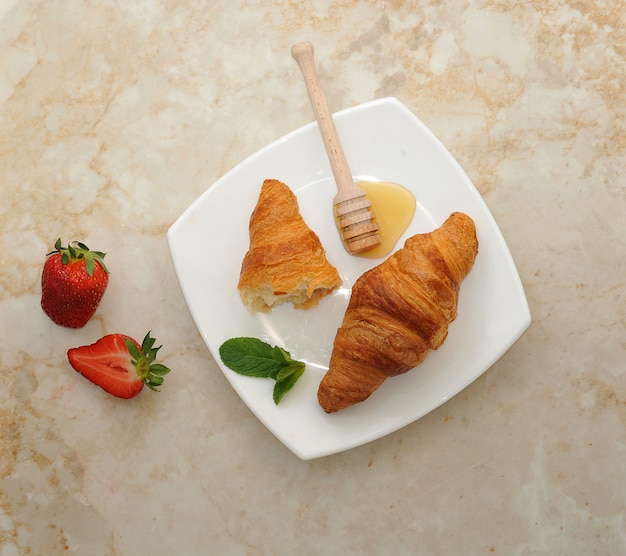 Croissant dois em um prato branco regado com mel