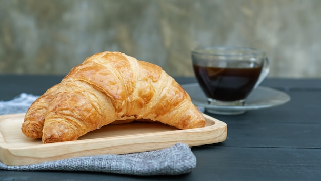 Croissant e café preto na mesa