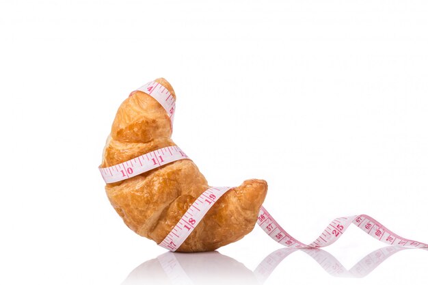 Croissant e fita de medição .. junk food, obesidade ou conceito saudável de alimentos