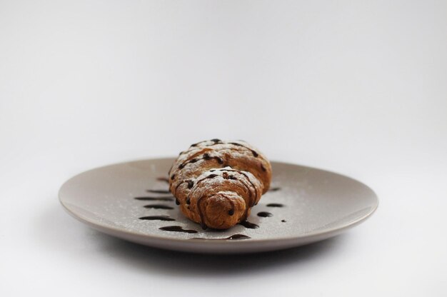 Croissant encogido por chocolate y azúcar en polvo en el plato gris