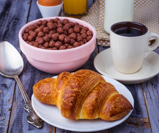 Croissant, floco de cereais, café, leite, suco de laranja, ovo cozido no café da manhã