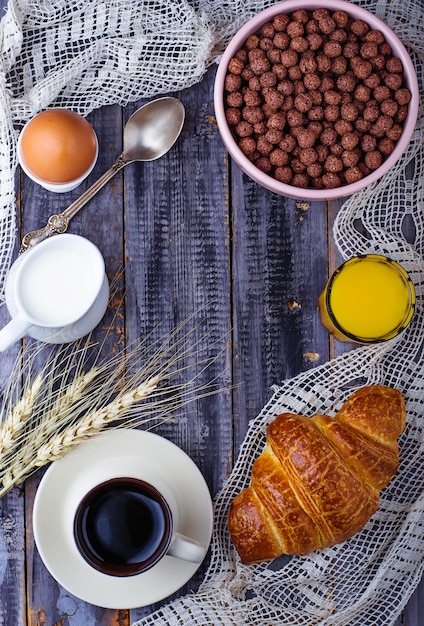 Croissant, floco de cereais, café, leite, suco de laranja, ovo cozido no café da manhã