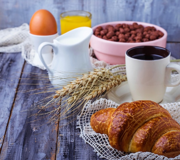 Croissant, floco de cereais, café, leite, suco de laranja, ovo cozido no café da manhã