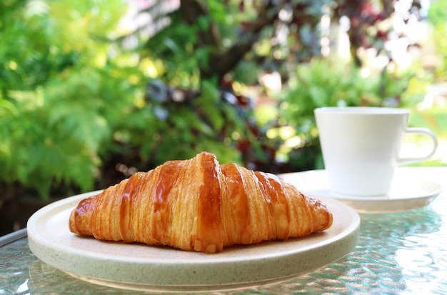 Croissant francês com café em uma mesa de jardim