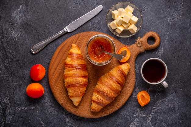 Croissant francés Croissants recién horneados con café con mantequilla de mermelada sobre un fondo de piedra oscura