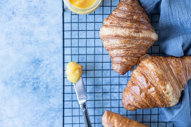 Croissant francés Croissants recién horneados con miel sobre fondo de hormigón azul