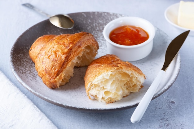 Un croissant francés recién horneado con mantequilla y mermelada